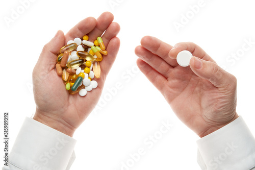 Man hand getting one pill from handful of pills, tablets, vitamins, drugs, capsules isolated on white background. White shirt, business style. Health care concept. Pharmaceutical industry. Pharmacy.