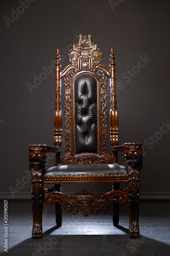Antique wooden carved armchair against a dark background.