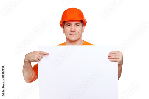Portrait smiling middle-aged handsome worker wearing orange hard hat, looking to the camera and holding blank sheet © Serhii