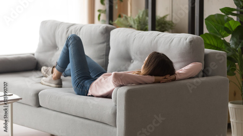 Tranquil girl lying on sofa in modern cozy living room.