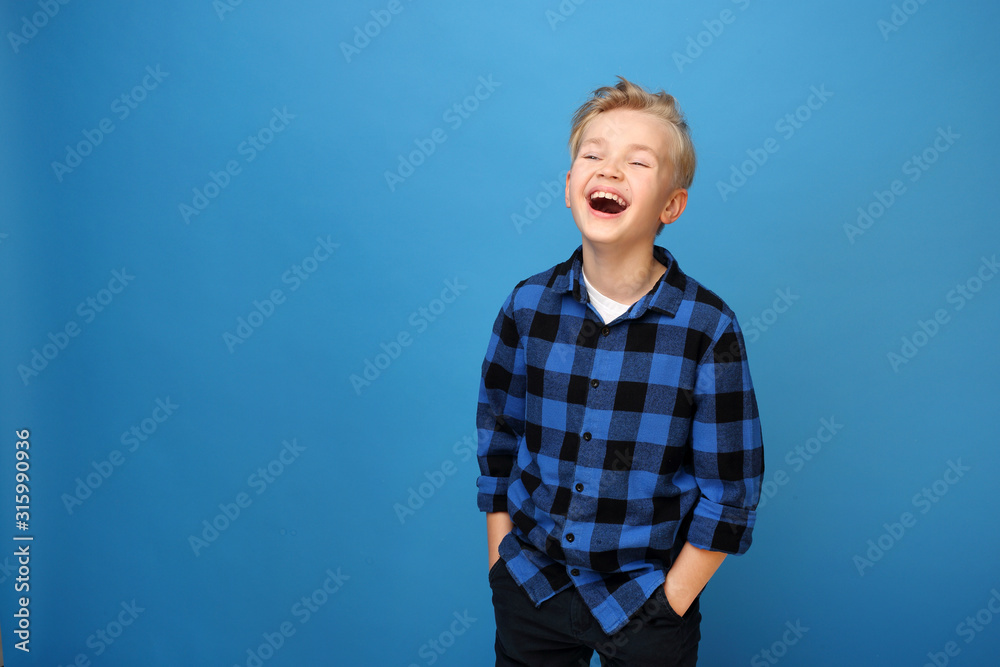 Happy child, laughing boy. Happy, smiling boy on a blue background expresses emotions through gestures. - obrazy, fototapety, plakaty 