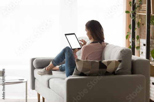 Papier peint Young woman holding tablet with blank screen back view.