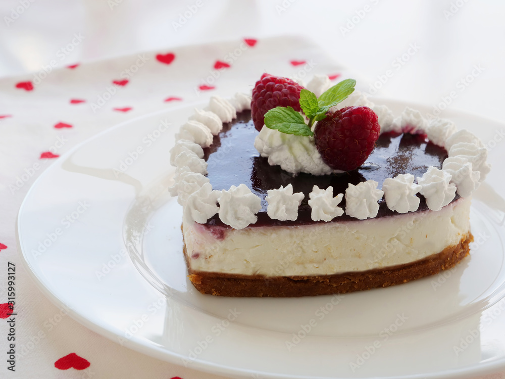 Heart shaped cheesecake with raspberries, graham cracker crust, cream cheese filling and berry jelly icing for Valentine's Day