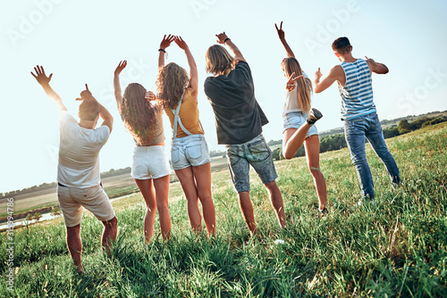 People group outdoor countryside raise arms rear back view friends holding hands up summer day