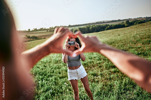 Closeup shot of young man and woman making heart shape with hand. photo