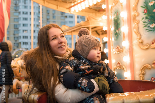 Mother and child on the carousel. Vintage carousel. The winter fair. Christmas fair. Happy family.