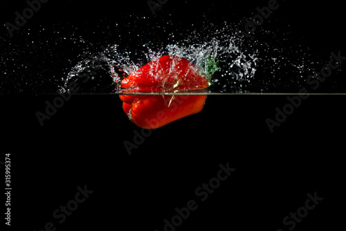 Red fresh paprika splash in water on a black background.
