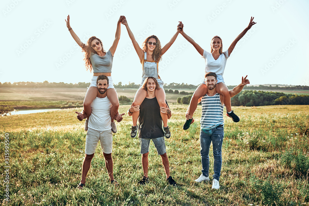 Just having fun. Handsome young people with attractive girlfriends a piggy back ride while walking on nature Just having fun. Handsome young people with attractive girlfriends a piggy back ride while walking on nature