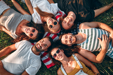 Group of young people are studying together in university. Students outdoors lying on american flag together.
