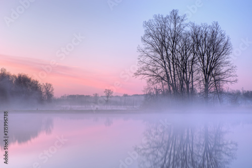 Dawn landscape of foggy Jackson Hole Lake with reflections in calm water, Fort Custer State Park, Michigan © Dean Pennala