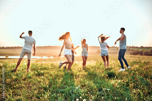 Happiness Friends funny dance on the field under sunset sunlight in summer sunny day.