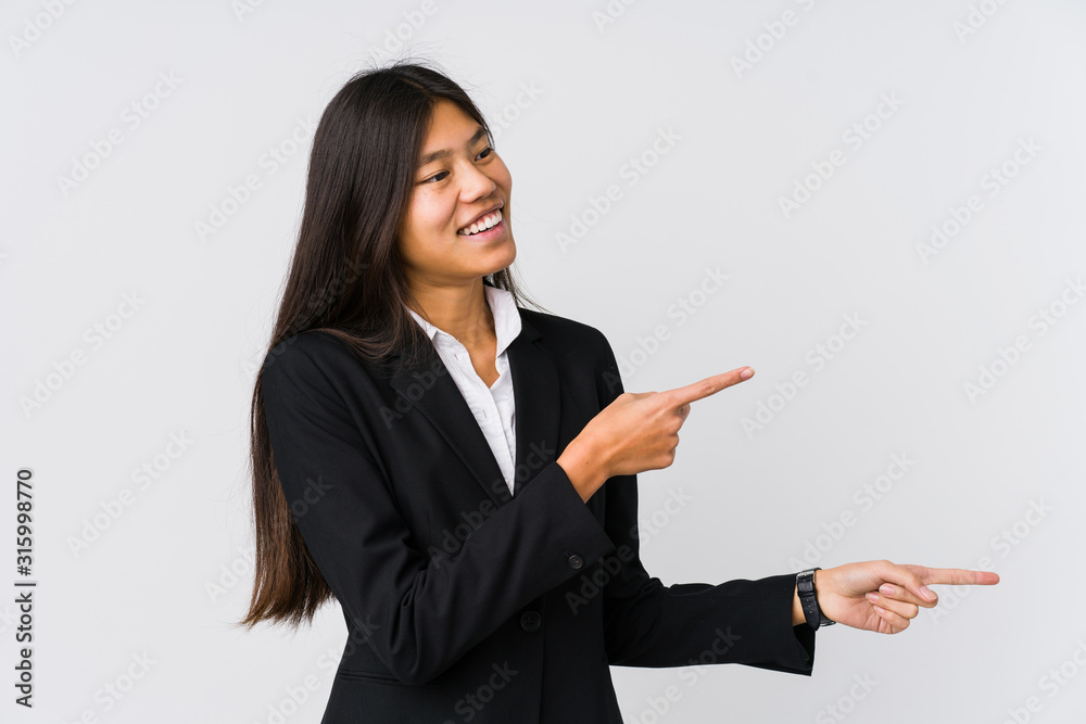 Young asian business woman excited pointing with forefingers away. Young asian business woman excited pointing with forefingers away.