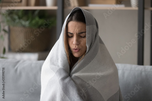 Unhealthy young woman feeling cold, covering in plaid.