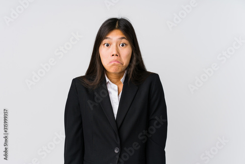 Young asian business woman shrugs shoulders and open eyes confused.