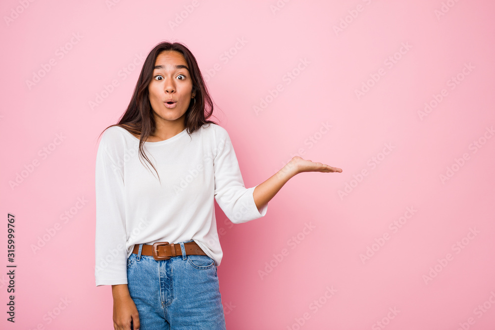 Young mixed race indian woman impressed holding copy space on palm. Young mixed race indian woman impressed holding copy space on palm.