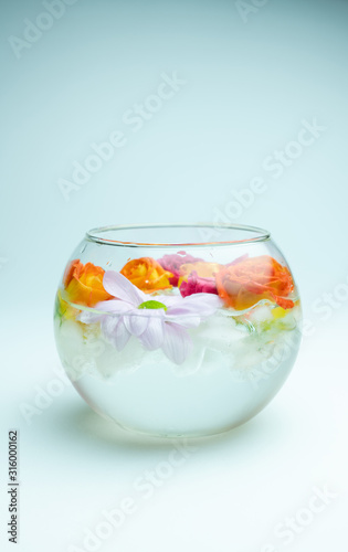 Spray roses and chrysanthemum in aquarium with ice cubes on white background