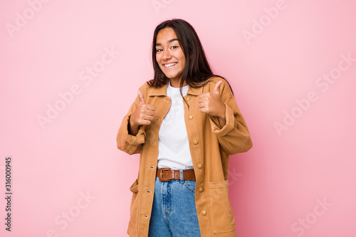 Young mixed race indian woman isolated raising both thumbs up, smiling and confident. © Asier