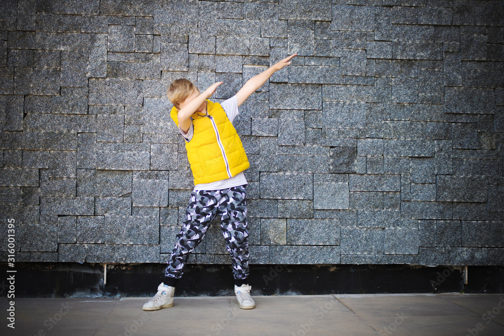 Small boy dabbing against brick wall.