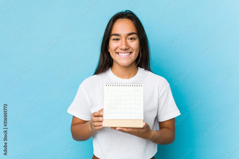 Young indian woman happy holding a calendar isolated Young indian woman happy holding a calendar isolated