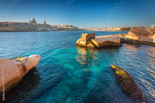 Rocky coastline of Malta and at the Valletta city at sunrise.