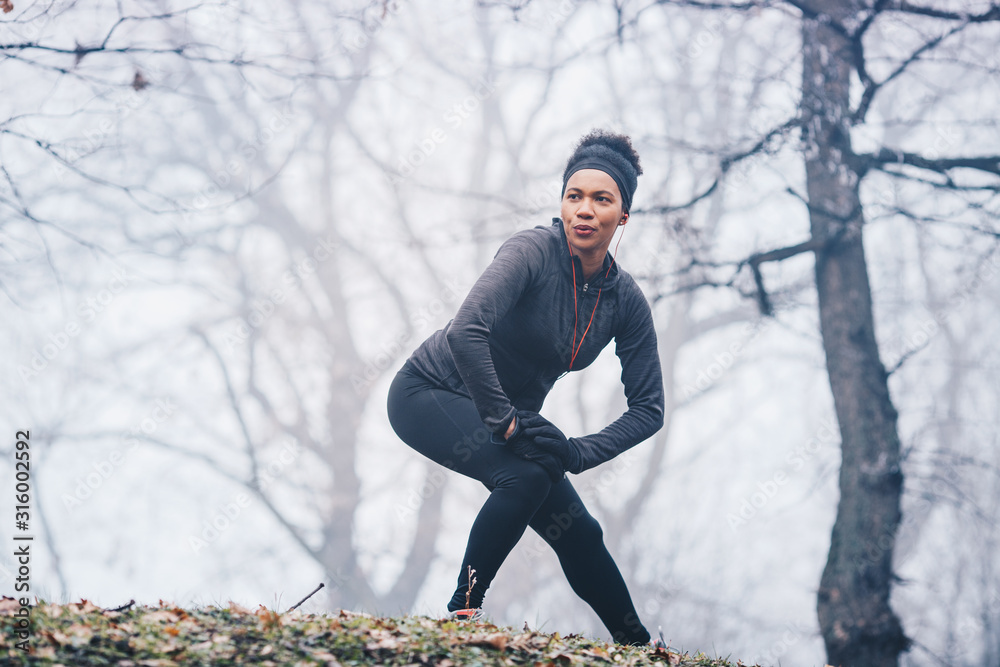 Fototapeta premium A woman warming up for exercise on a misty morning in nature.