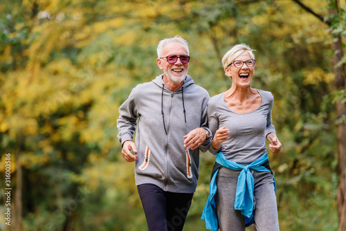 Tablou pe pânză Cheerful active senior couple jogging in the park