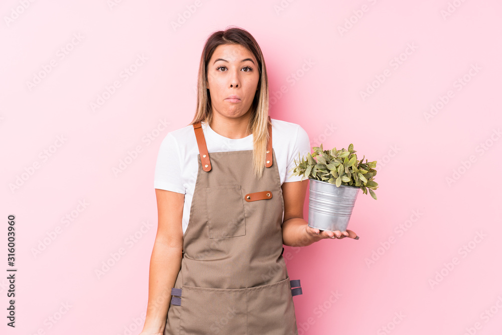 Young gardener caucasian woman isolated shrugs shoulders and open eyes confused. Young gardener caucasian woman isolated shrugs shoulders and open eyes confused.