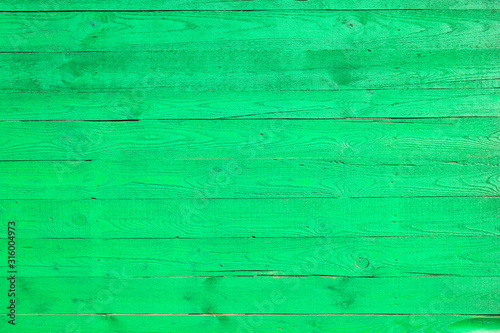 Light green painted wooden fence made of pine boards, green wall background, pine wood texture