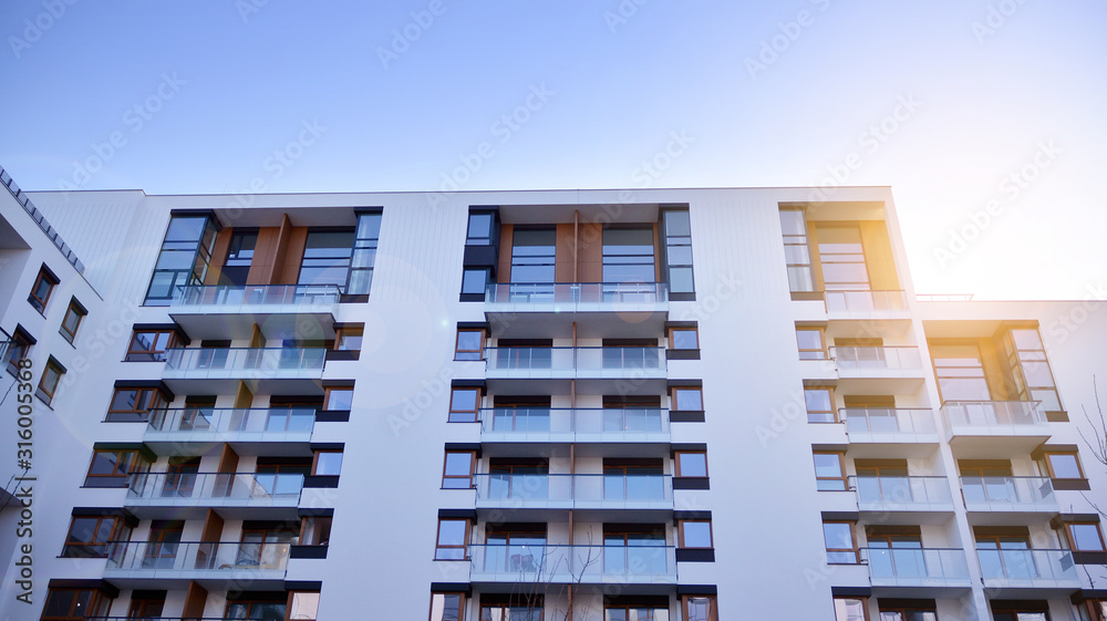 Modern multi story building being lit by the setting sun at afternoon. New apartment house residential building outdoor concept. Modern multi story building being lit by the setting sun at afternoon. New apartment house residential building outdoor concept.