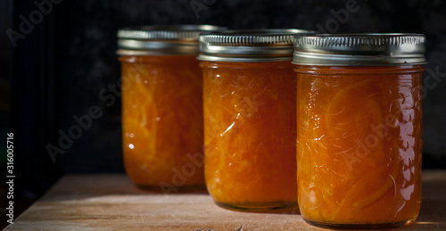 Three mason jars of marmalade on a board photo