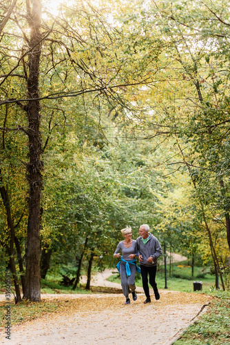 Cheerful active senior couple jogging in the park. Exercise together to stop aging. © lordn