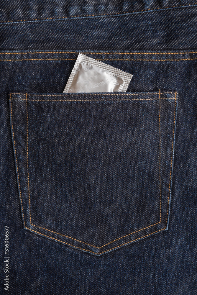 Condom package in the back pocket of dark blue jeans. Protected sex and health care concept. Copy space. Closeup