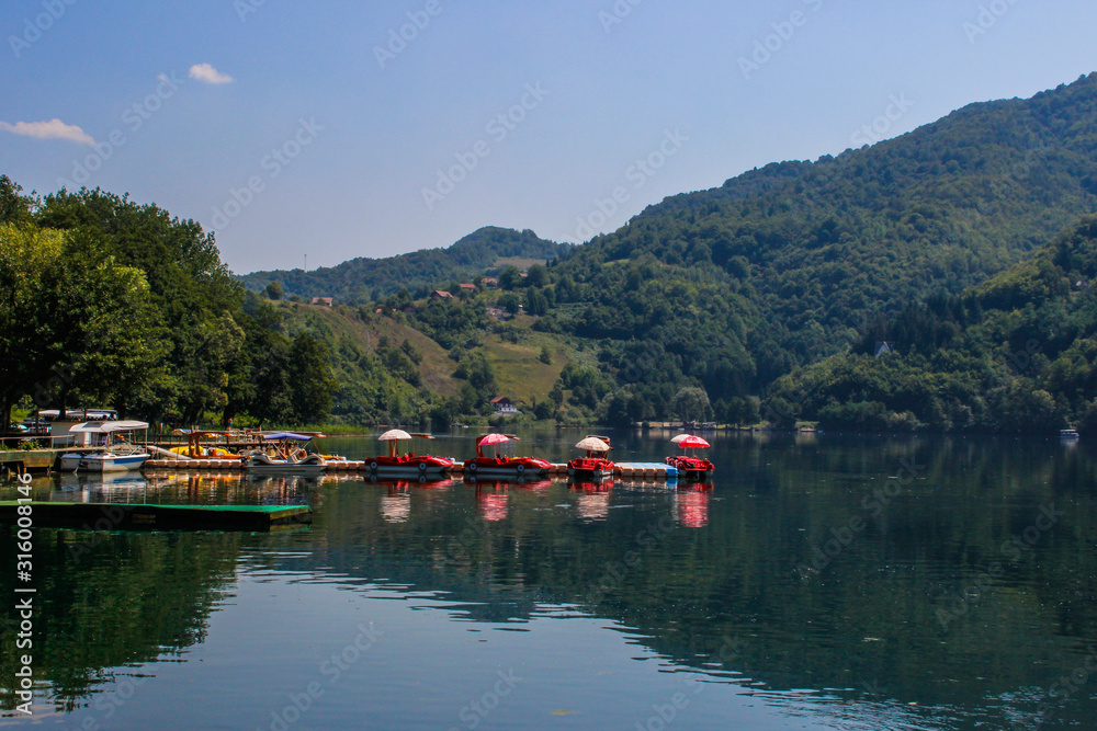  calm beautiful lake surrounded by forests and tourist boats. Sights of Bosnia and Herzegovina.