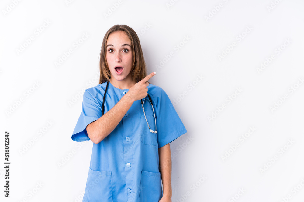 Young nurse woman isolated pointing to the side Young nurse woman isolated pointing to the side