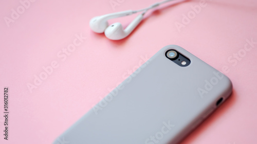 Smartphone and earphones isolated on the pink background.