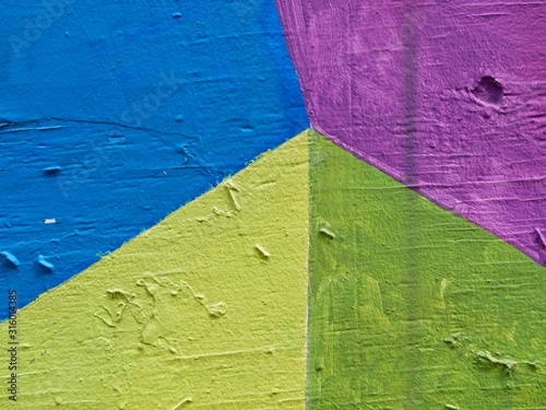 Green, yellow, and blue paint on textured, wooden wall in downtown Austin, Texas for abstract background.