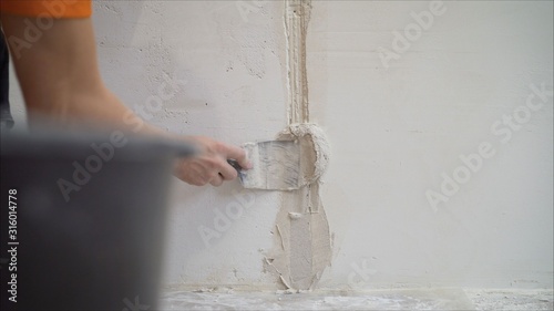 Worker using the trowel for plastering the concrete wall at the construction site. Making the smoothness and flat the surface of cement wall by wooden trowel. Labor day. 