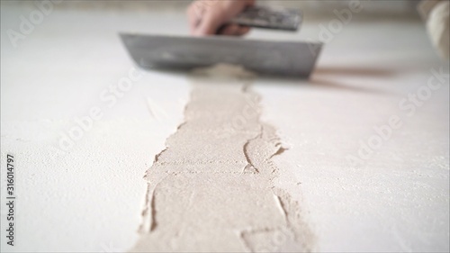Worker using the trowel for plastering the concrete wall at the construction site. Making the smoothness and flat the surface of cement wall by wooden trowel. Labor day. 