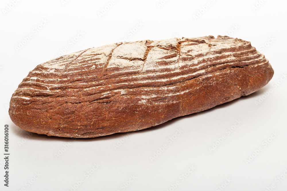 A whole loaf of fresh black rye bread with cuts from a knife on top of it and sprinkled with white flour isolated on a white background. Healthy eating concept.