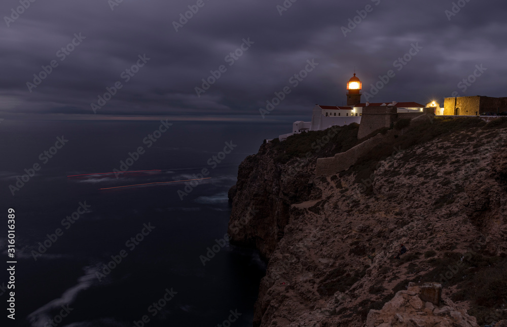Beautiful rocky coastline landscape with lighthouse on Sao Vincente cape. Farol doCabo de Sao Vicente, Algarve, Portugal.   