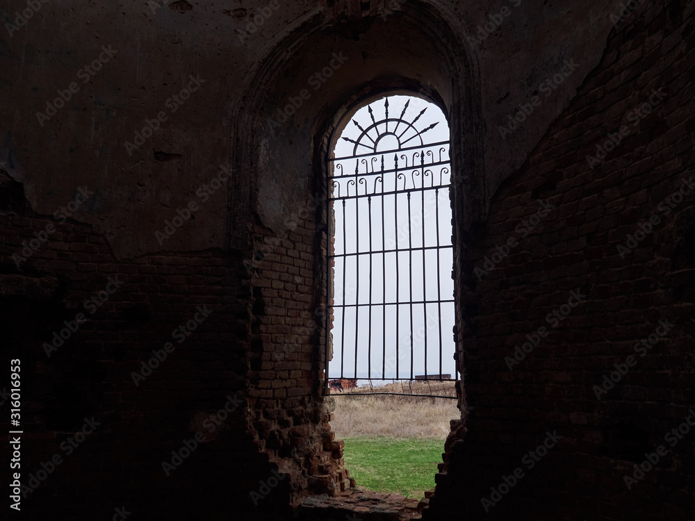 Alone window with bars in a dark old building overlooking the field