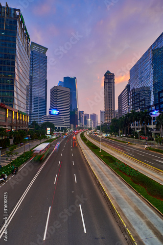 Light trails on the busy traffic surrounded by Jakarta business office buildings with colorful sky © Mujibur Rohman