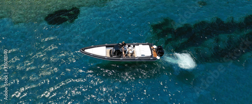 Aerial drone ultra wide top down photo of luxury rib inflatable with wooden deck cruising in deep blue open ocean sea