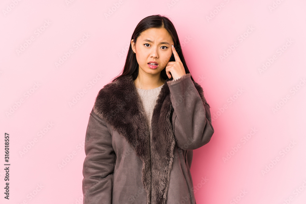 Young chinese woman wearing a coat isolated showing a disappointment gesture with forefinger.