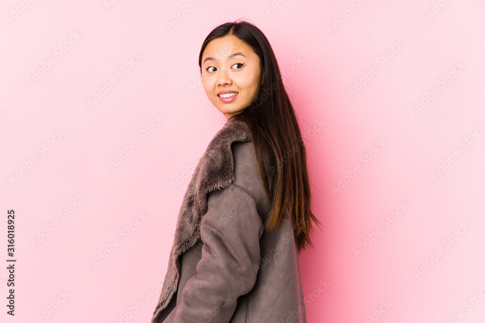 Young chinese woman wearing a coat isolated looks aside smiling, cheerful and pleasant. Young chinese woman wearing a coat isolated looks aside smiling, cheerful and pleasant.