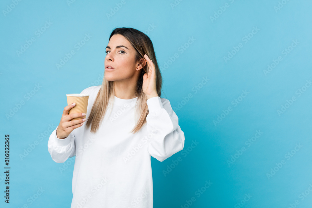 Young caucasian woman holding a takeaway coffee trying to listening a gossip. Young caucasian woman holding a takeaway coffee trying to listening a gossip.
