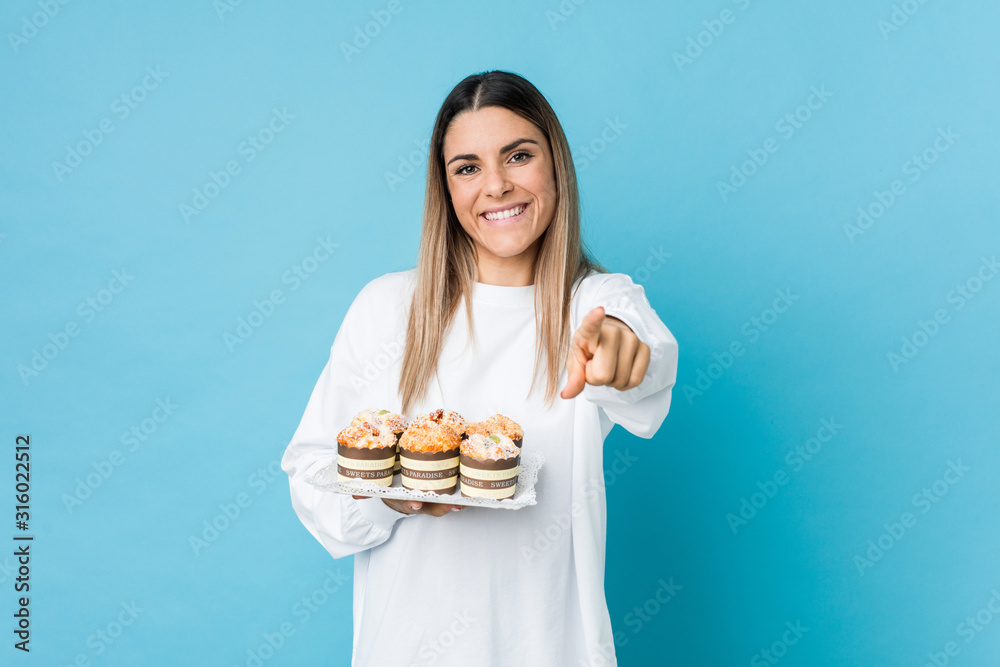 Young caucasian woman holding a sweets cake cheerful smiles pointing to front. Young caucasian woman holding a sweets cake cheerful smiles pointing to front.