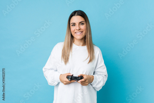 Young caucasian woman holding a game controller happy, smiling and cheerful.