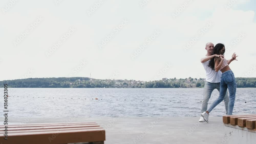 There is a lake and forest on a background. A couple is dancing. Man and woman are professional dancers. There is a lake and forest on a background. A couple is dancing. Man and woman are professional dancers.