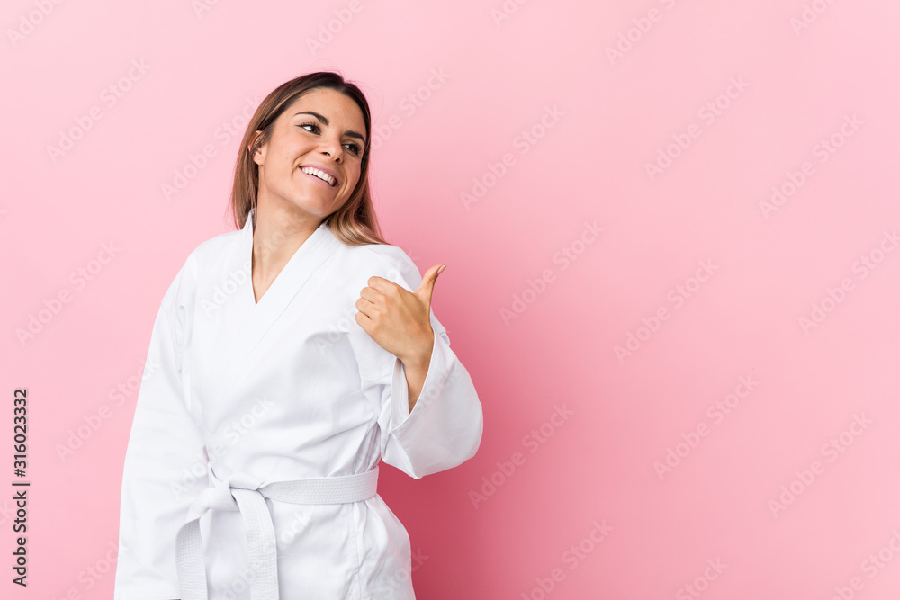 Young karate woman points with thumb finger away, laughing and carefree. Young karate woman points with thumb finger away, laughing and carefree.